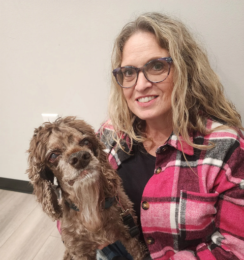 woman holds a small, brown shaggy dog